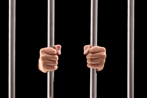 Male hands holding prison bars isolated